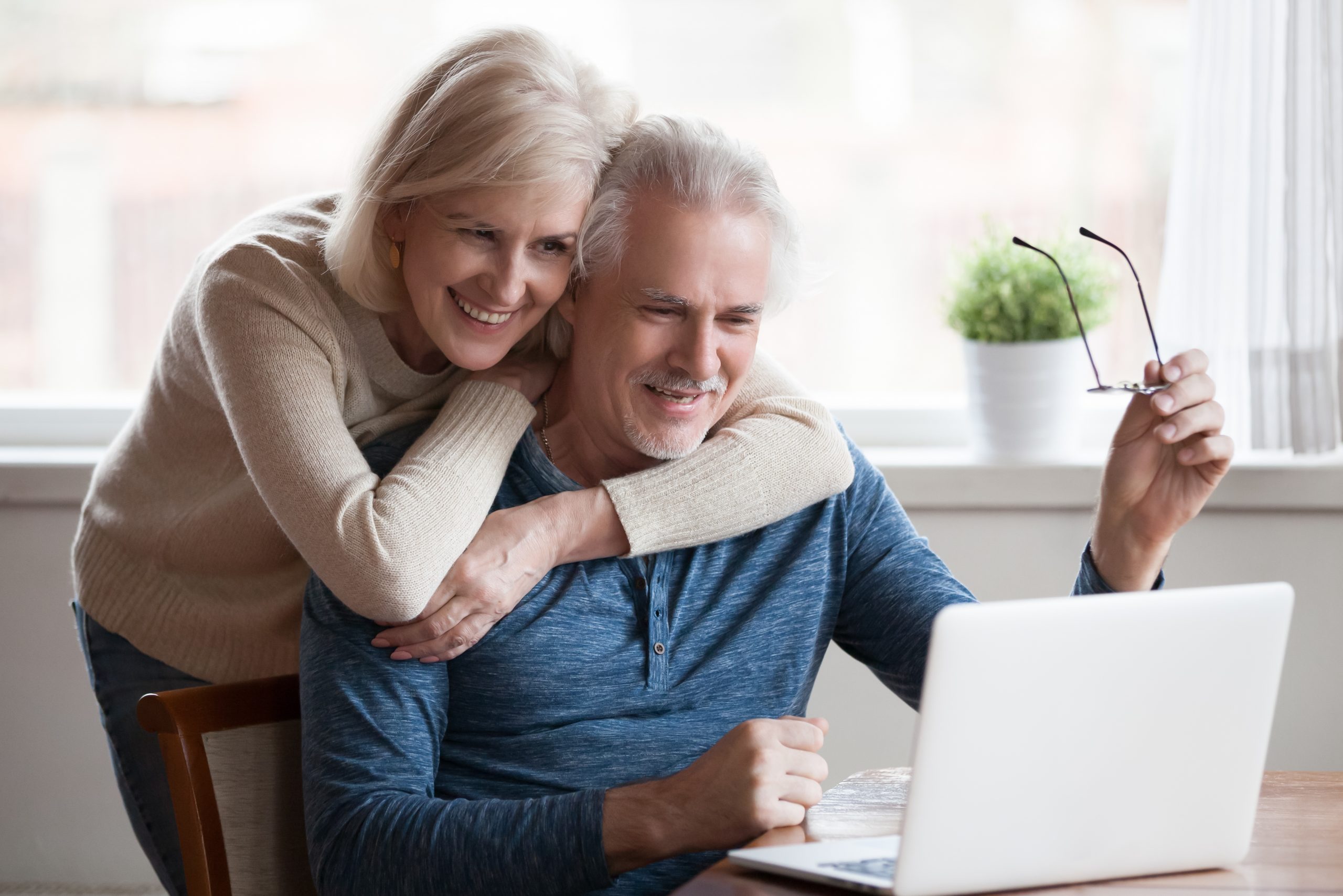 Senior,Middle,Aged,Happy,Couple,Embracing,Using,Laptop,Together,,Smiling